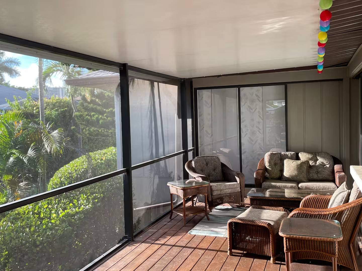 Screened lanai seating area with tropical greenery outside
