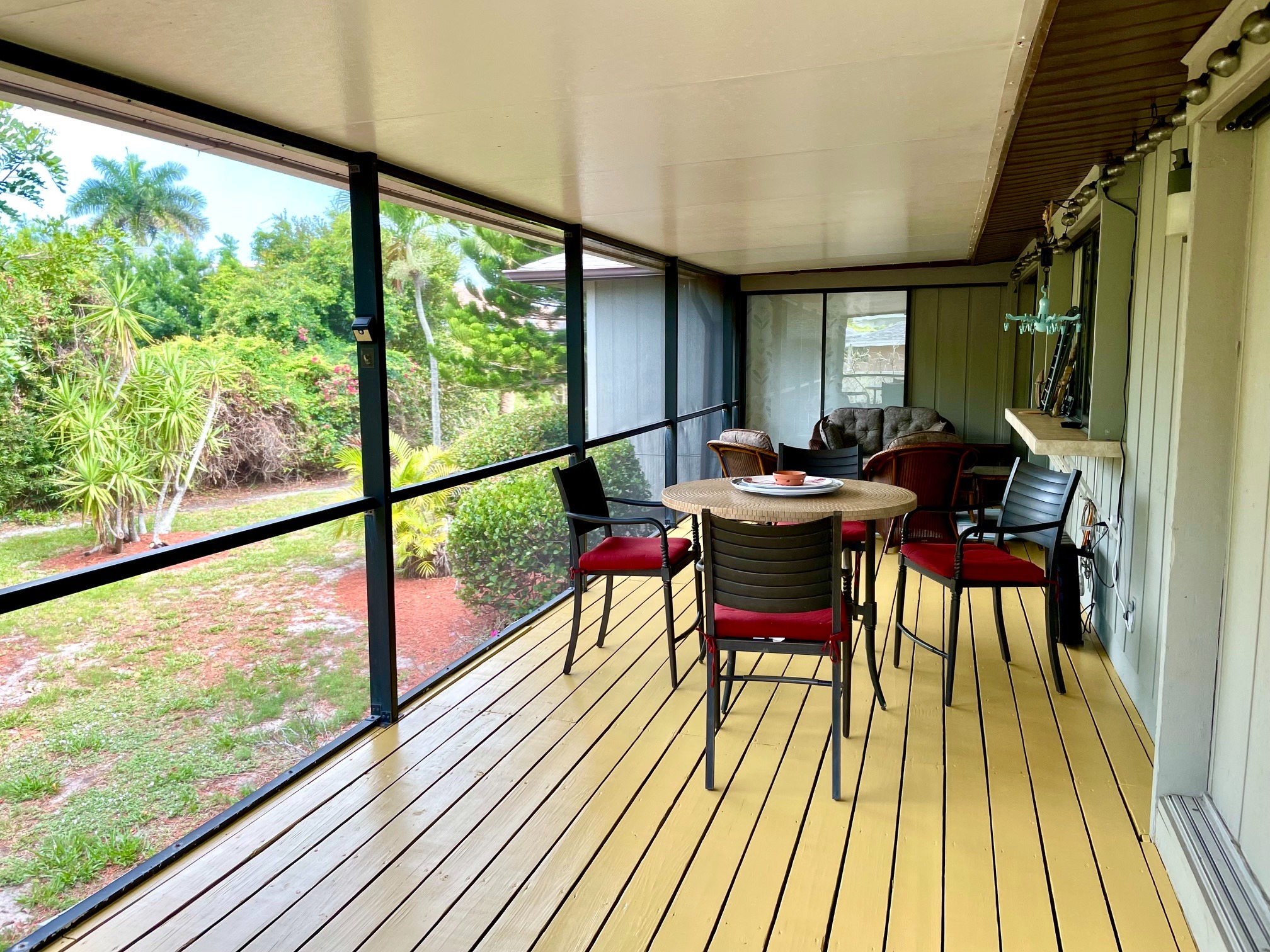 Screened lanai with dining table overlooking tropical landscaping
